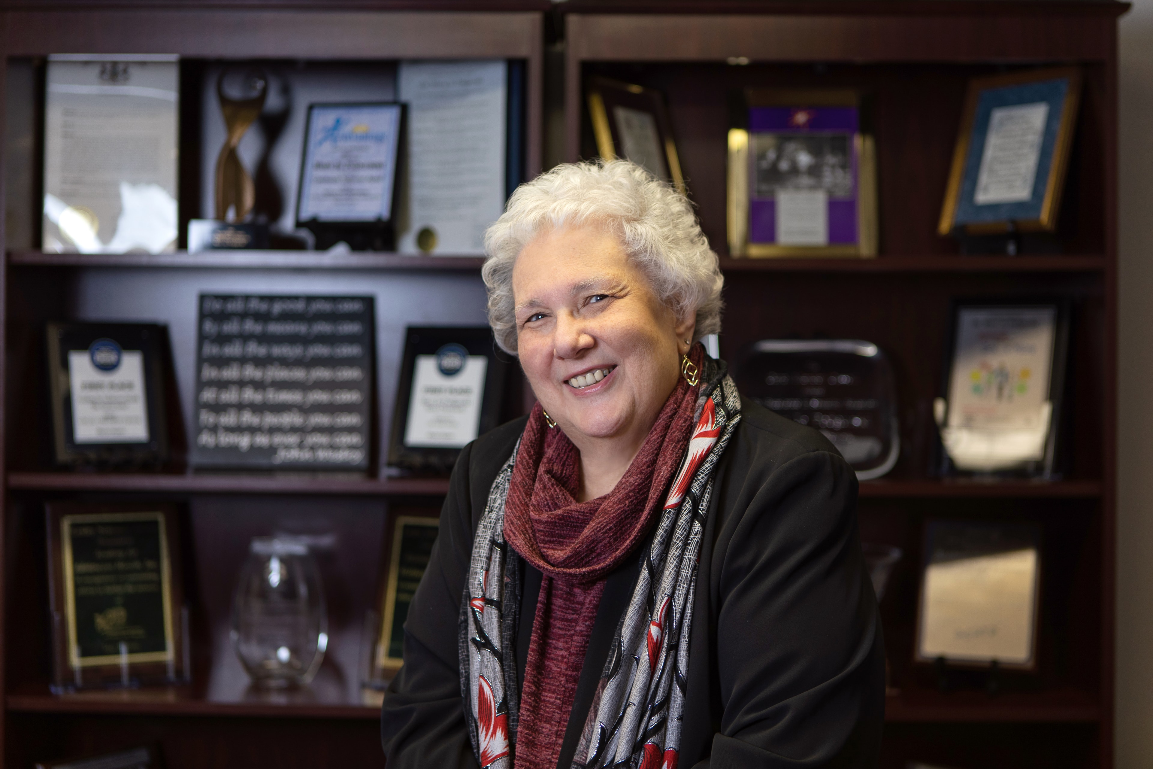Dr. Mary Jo Podgurski smiling in front of an awards display